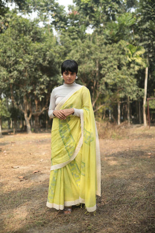 Person wearing handloomed organic cotton yellow saree dyed in azo free colors with hand block printed floral pattern with laces.