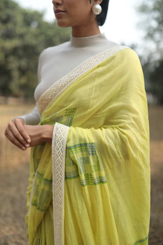 Person wearing handloomed organic cotton yellow saree dyed in azo free colors with hand block printed floral pattern with laces.
